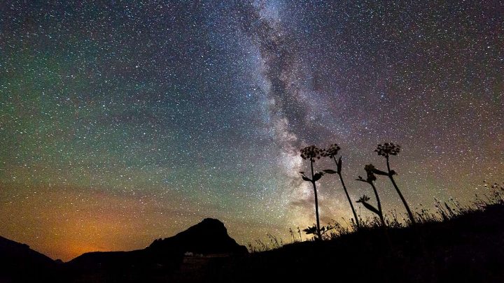 The Milky Way and countless stars above a dark mountain silhouette