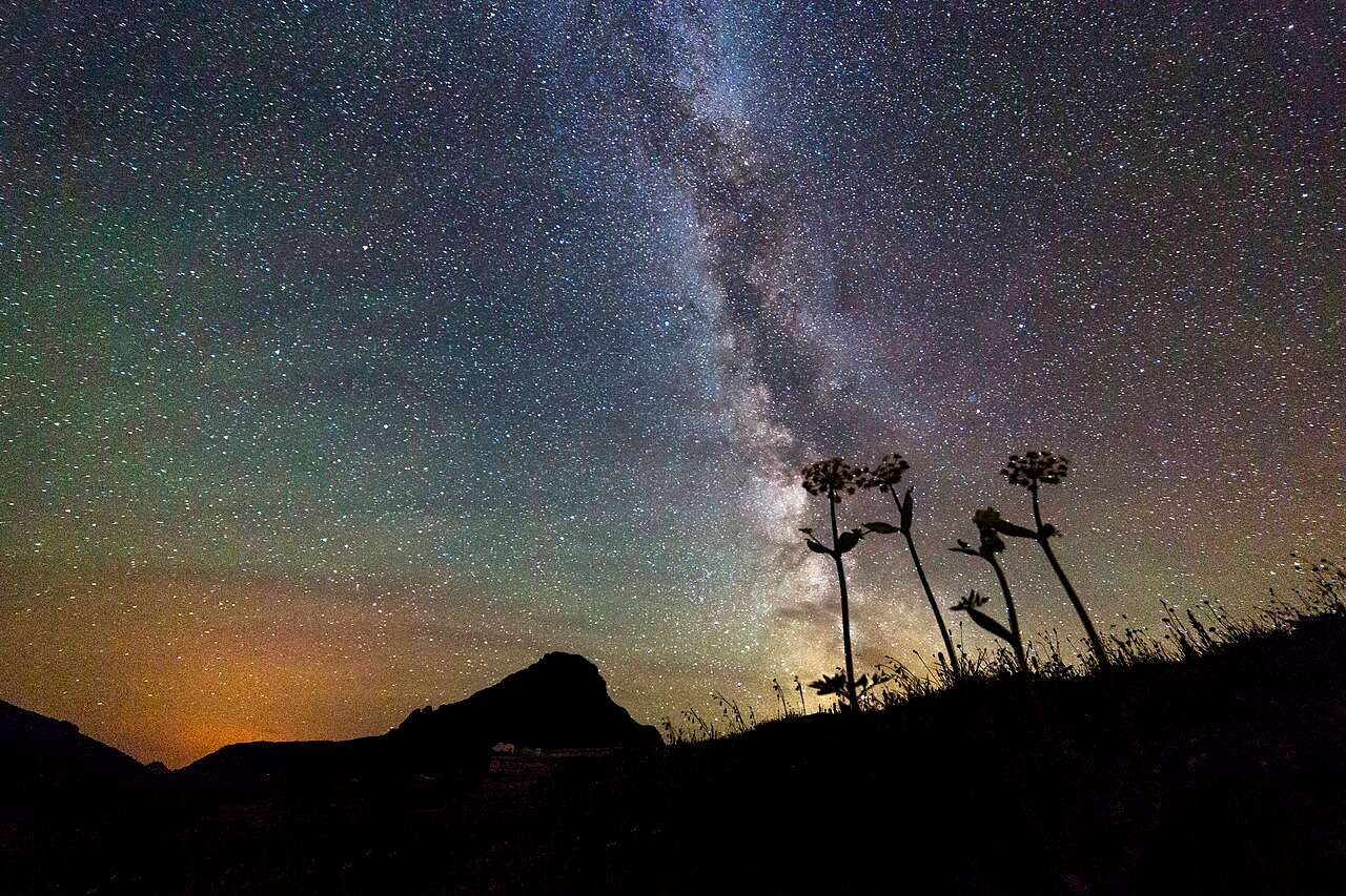 The Milky Way and countless stars above a dark mountain silhouette