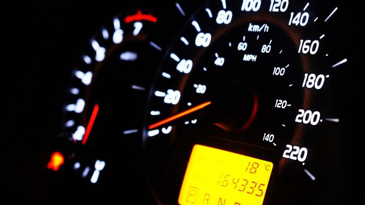 Illuminated car speedometer dial glowing against a dark dashboard