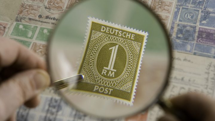 Magnifying glass enlarging a postage stamp in a collection