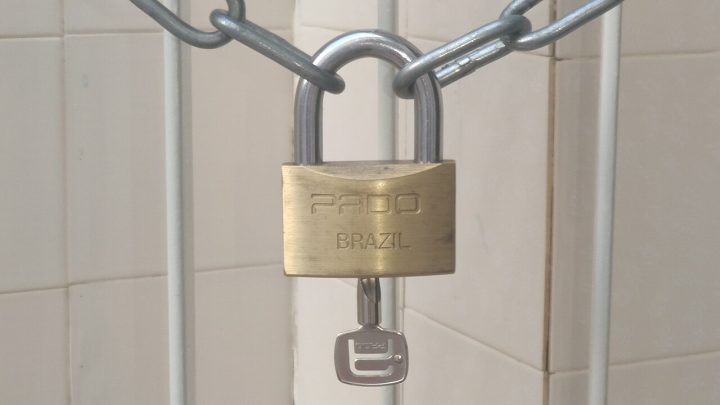 Brass padlock securing a metal chain